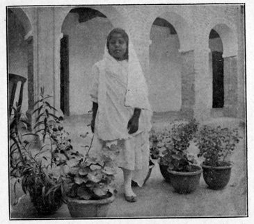 Woman standing near potted plants in courtyard