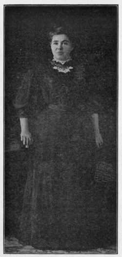 Portrait of woman in black dress, standing.