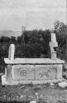 photograph of a stone grave above ground, adorned with crosses and a tombstone along with the portrait of the horse.