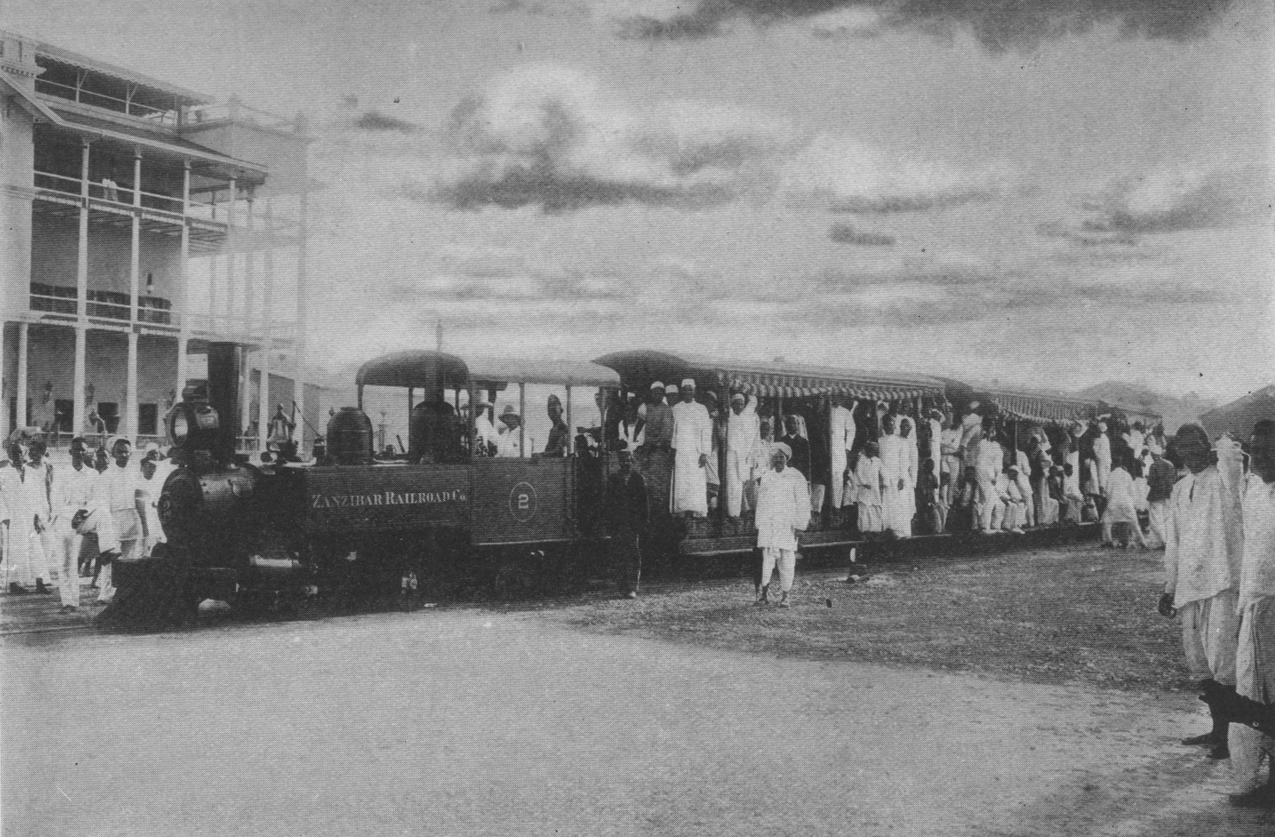 train with open-air cars and many people in light-colored clothing
