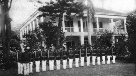 row of soldiers in front of two-story house with stacked porches