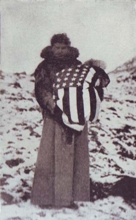 Person holding baby, wrapped in multiple layers of clothing and the Stars and Stripes American flag