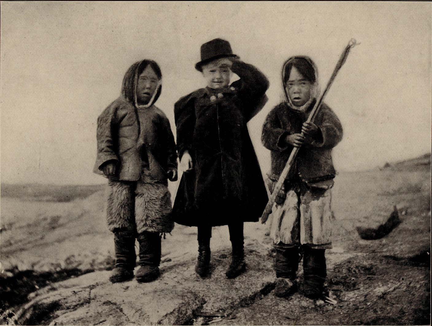 Three children standing together; Marie  in the middle holds her hat.