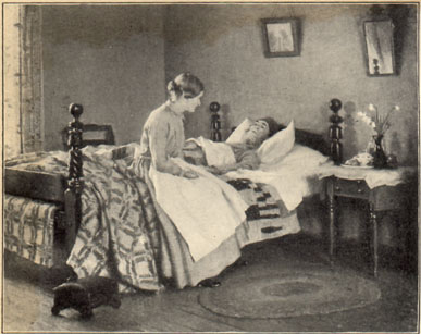 woman sitting on the edge of a bed, looking gently at the man lying down