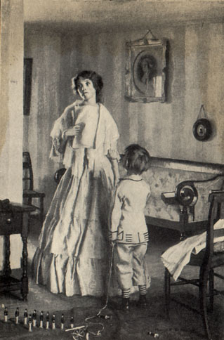 Woman in a long dress standing holding some papers as a child facing her looks up at her expectantly 
