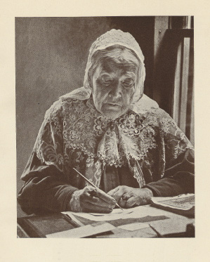 elderly lady in a cap writing at a desk