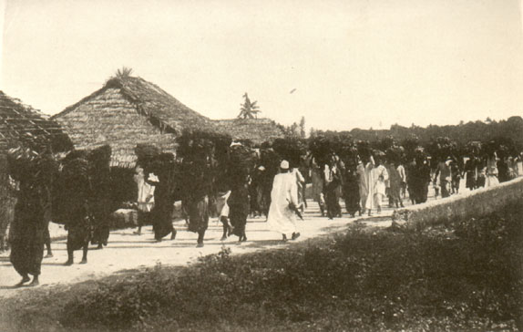 group of people laden with goods walking along a road