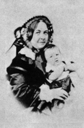 Woman holding a baby. They are both smiling.