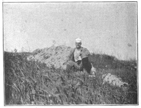 man sitting in field by stone ruins