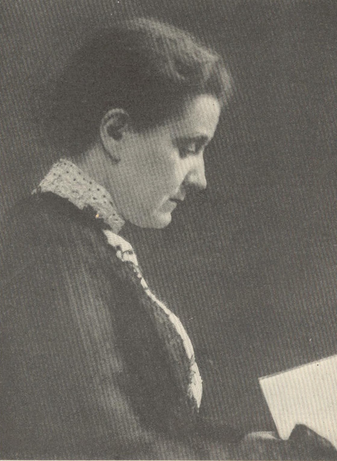 A woman in profile looking down at a book in her hands.