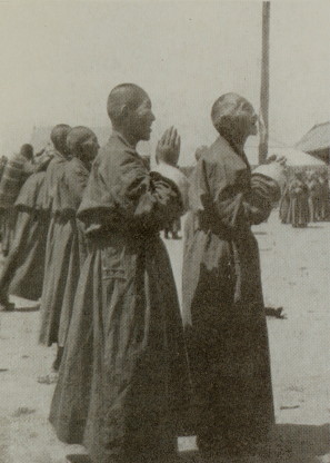 monks standing before temple, hands raised in prayer