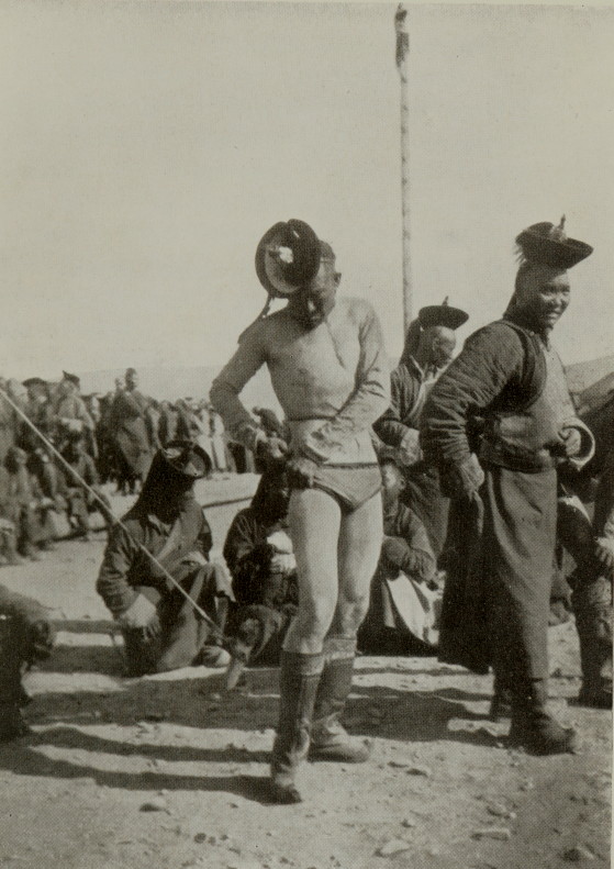 Mongolian man in wrestling gear standing before a crowd