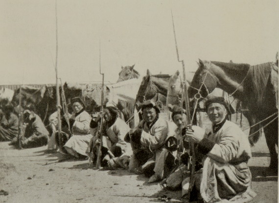 group of soldiers holding guns and sitting before their horses