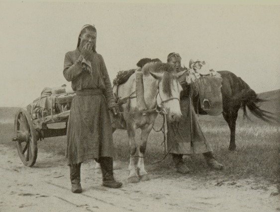 man and woman standing with a horse-drawn wagon