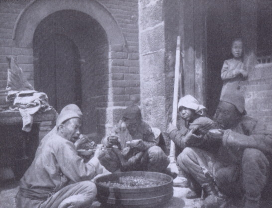 several servants eating around a large bowl set on the ground
