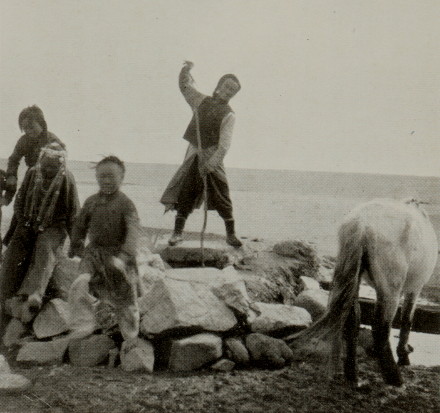 group of Mongolian men sitting and standing on large rocks