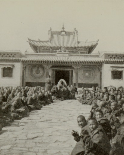 large group of men seated in front of an ornate temple entrance