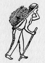 Man wearing pants carrying a walking stick. He has a load of wood on his back.