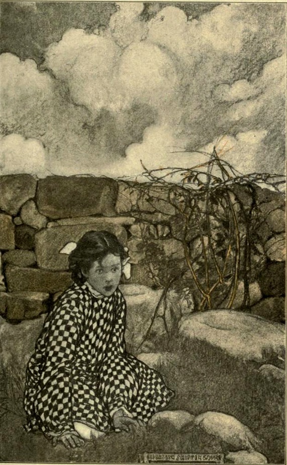 Girl sitting on the ground behind a stone wall.