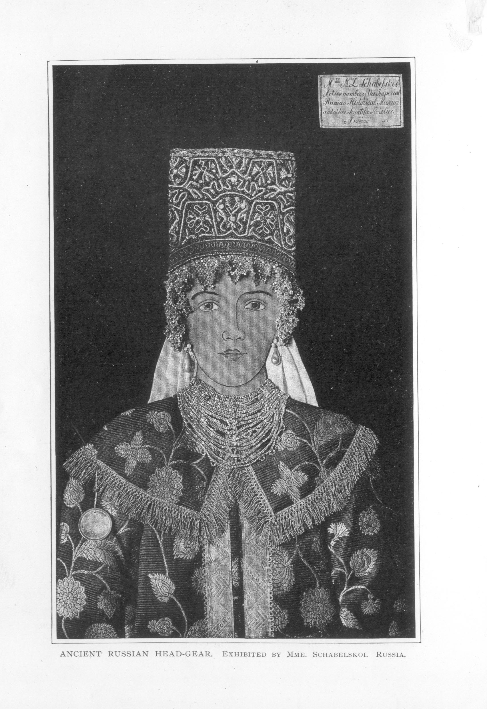 rectangular embroidered headdress with jeweled beadwork decorating rim on display with floral robe