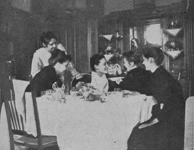 Five women sitting and talking at a table.