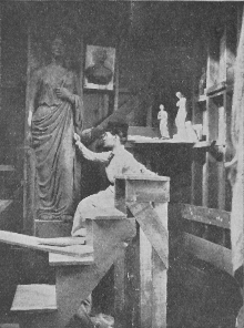 Woman sitting working in a room full of sculptures, large and small.