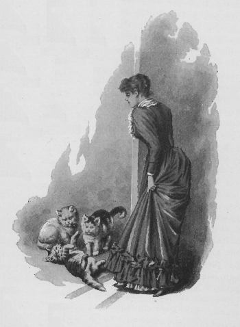 Woman standing and watching three cats play on the floor.