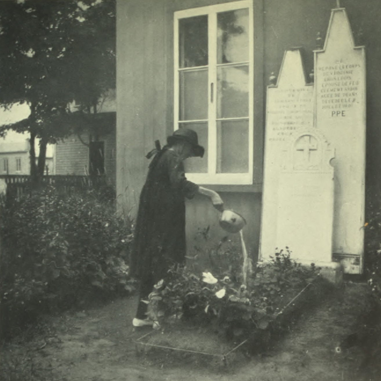 Woman watering flowers on a grave.