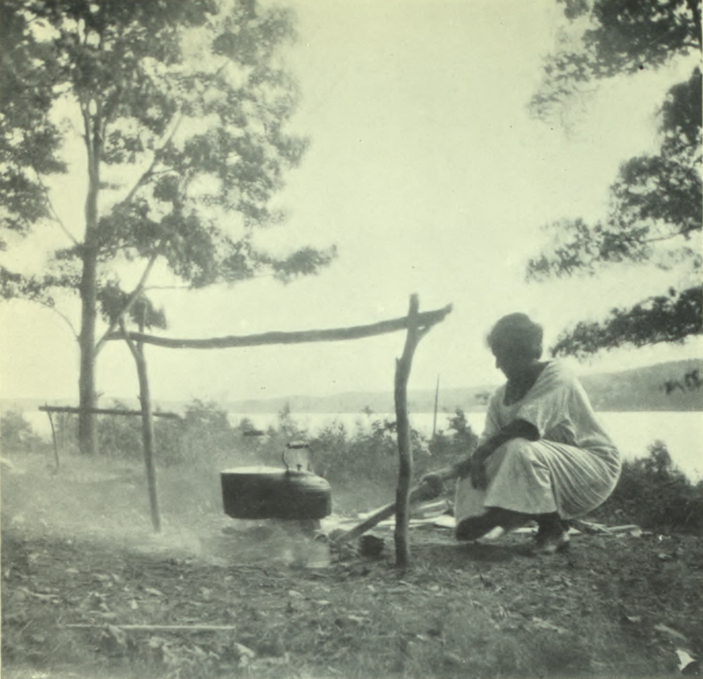 Woman tending to a cooking fire and food.