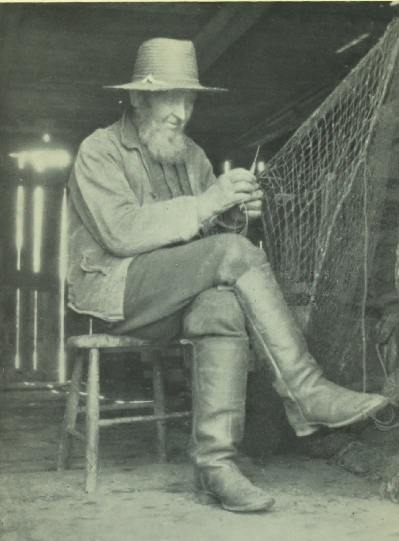 Man in a straw hat and fishing boots focused on the task at hand.