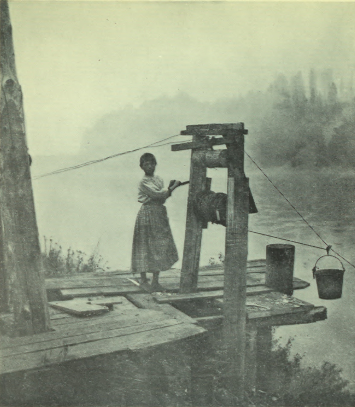 Girl on dock winding the the pulleys that fetch buckets of water.