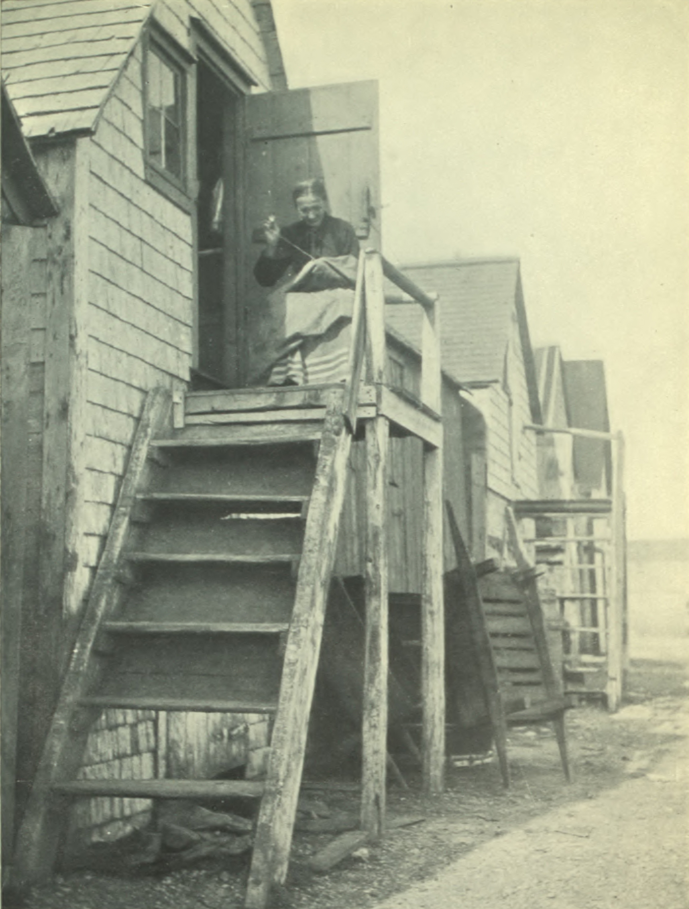 Woman sitting outside at the top of her stairs, weaving.