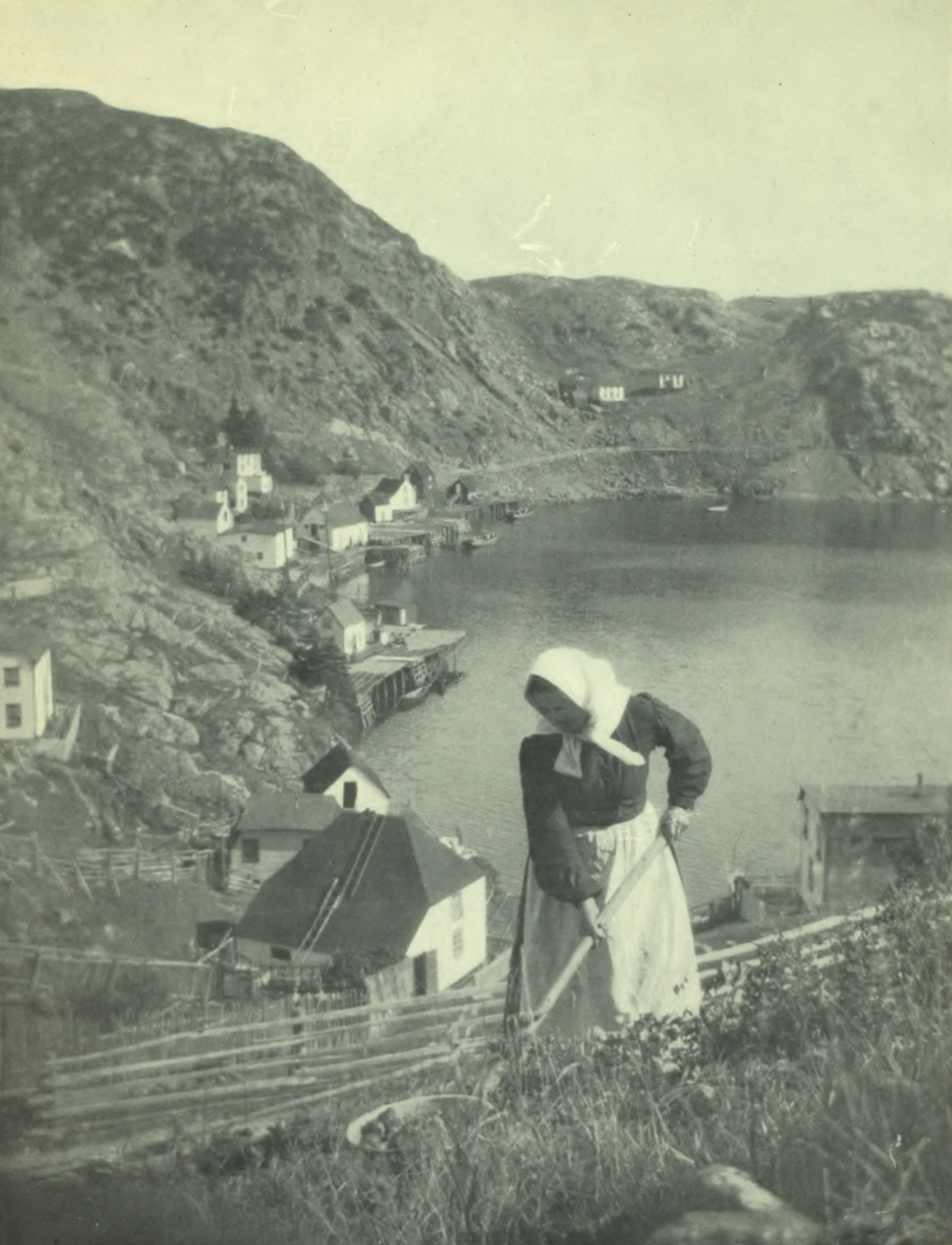 Woman gardening up in the hills. View of the inlet behind her.