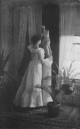 woman in long dress looking out the window of a room with potted plants