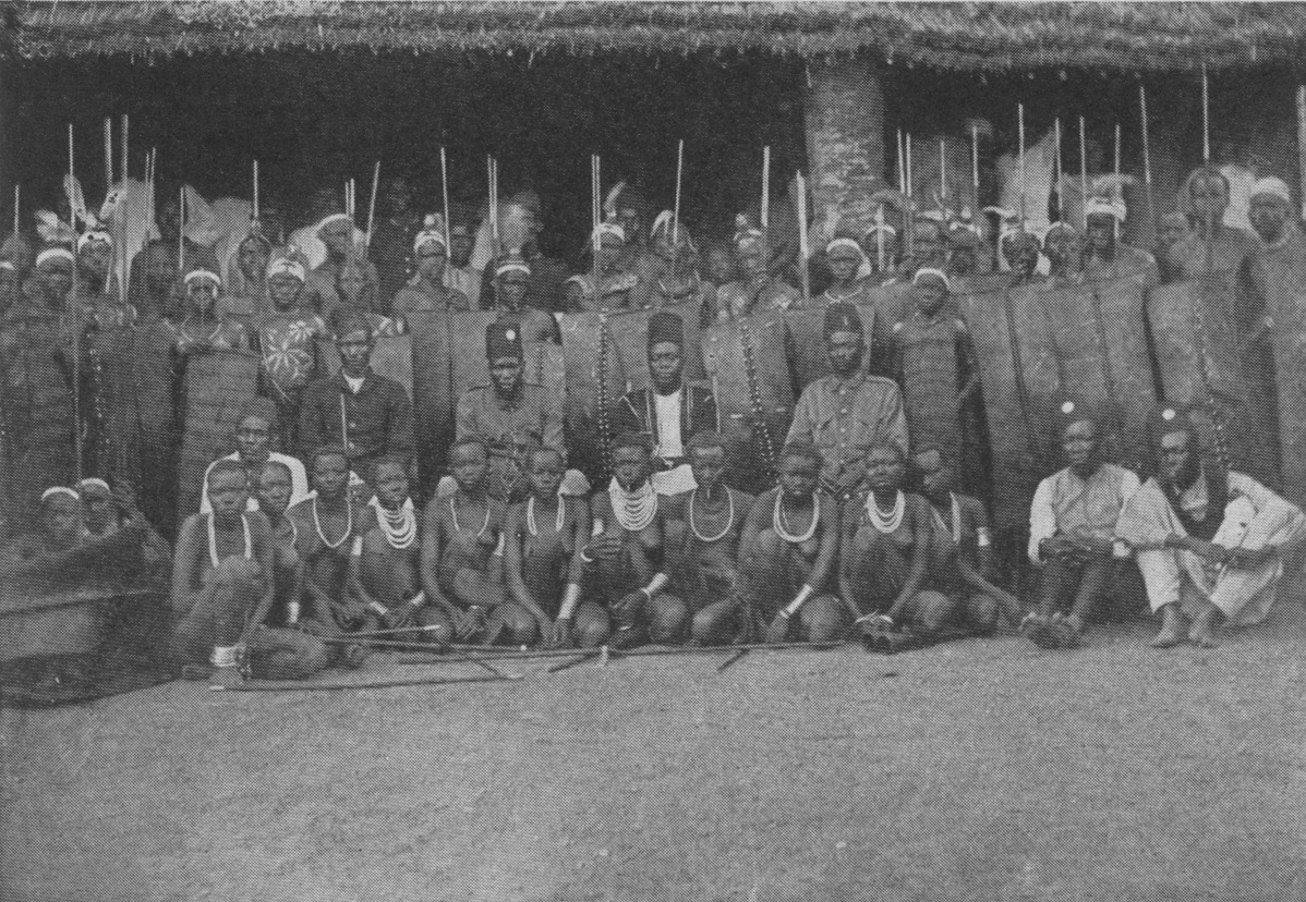 group of people posing; some standing with spears and shields, some seated