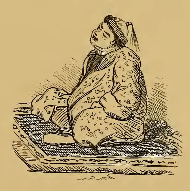 man wearing traditional garment sitting cross-legged on a carpet