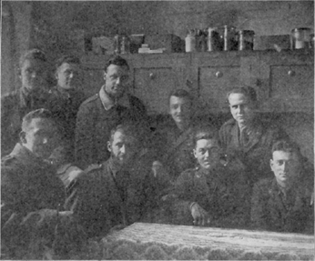 Portrait of nine men in two rows. The front row is sitting and the back one stands behind.