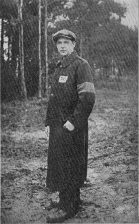 Portrait of a man standing with a wood behind him.