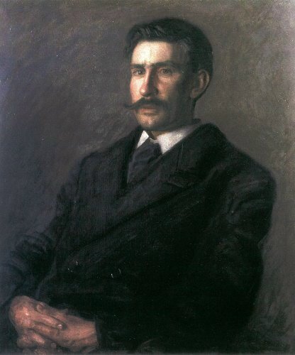 man with moustache and hands folded in lap