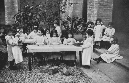 children gathered around a table, two of whom are holding bowls of food