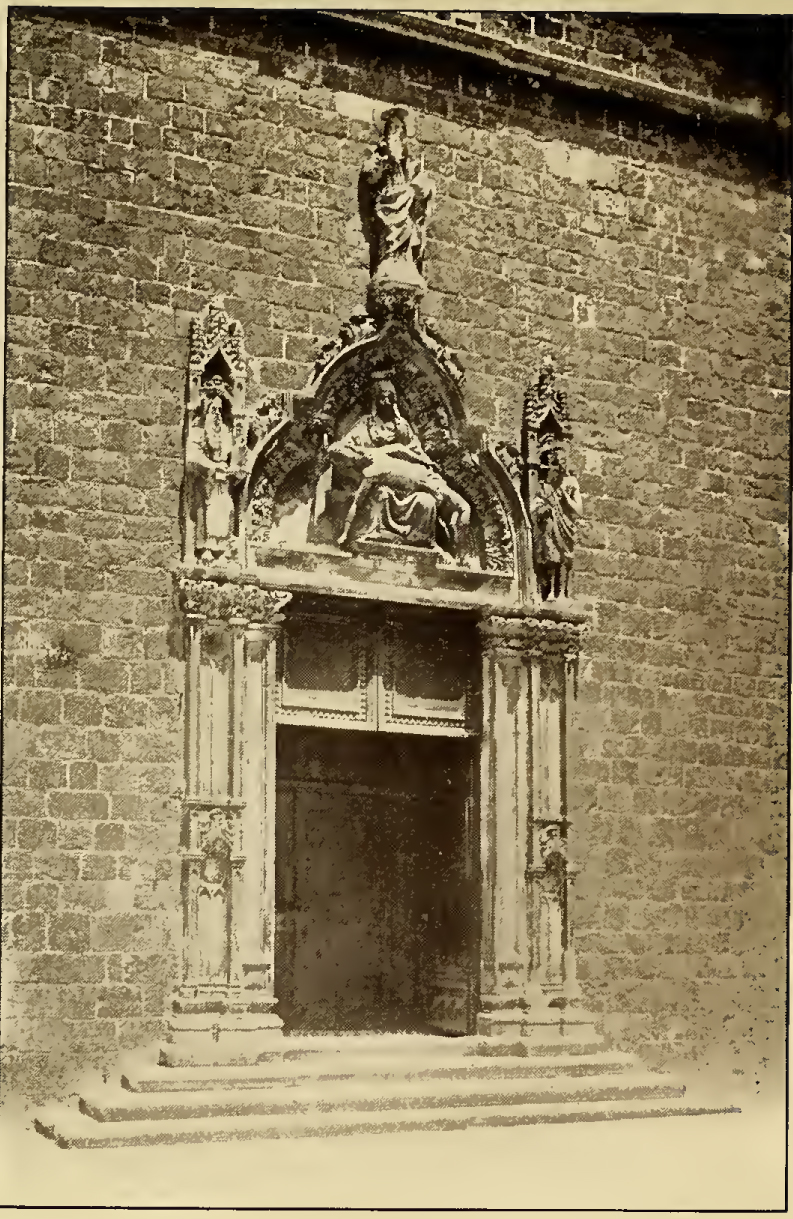 Doorway with stone carving above, depicting pietà with Mary cradling Christ. Caption: Venetian Gothic Doorway, Franciscan Church.