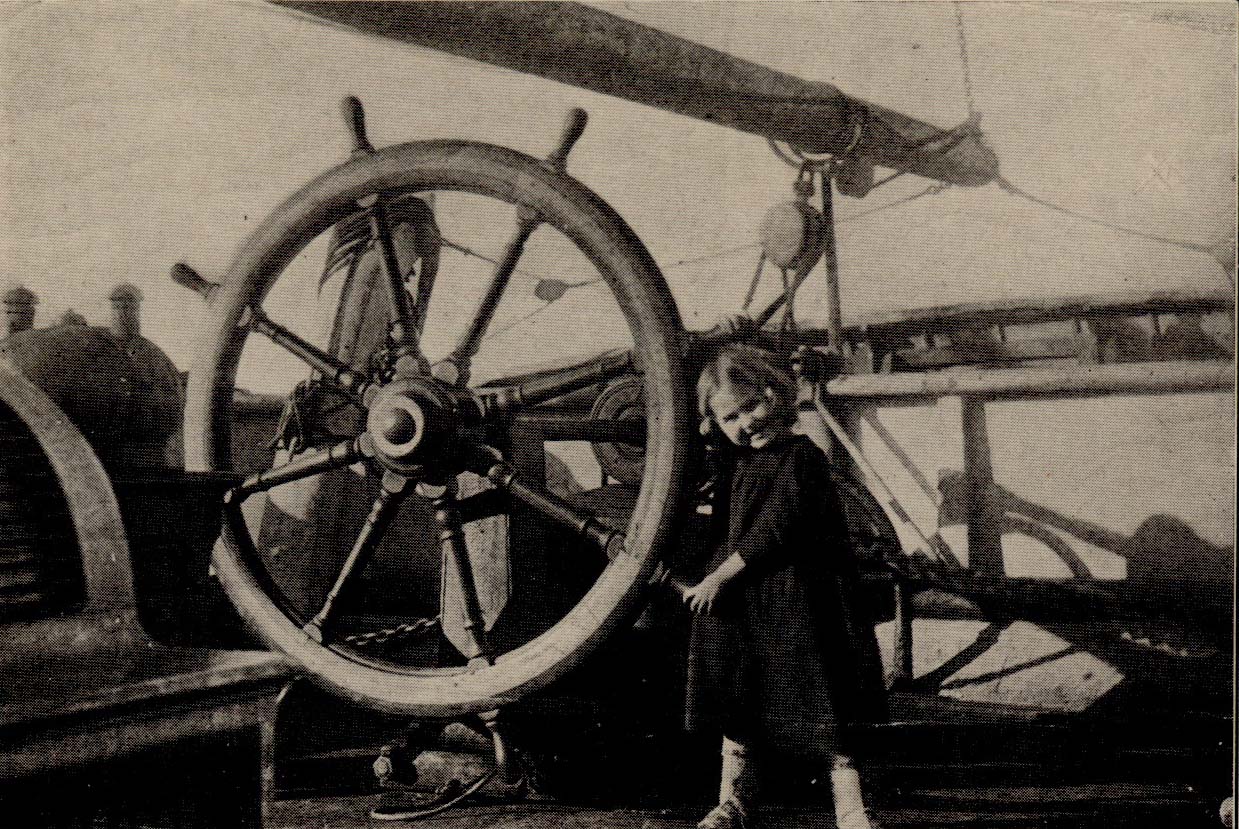 Child on deck holding the steering wheel.