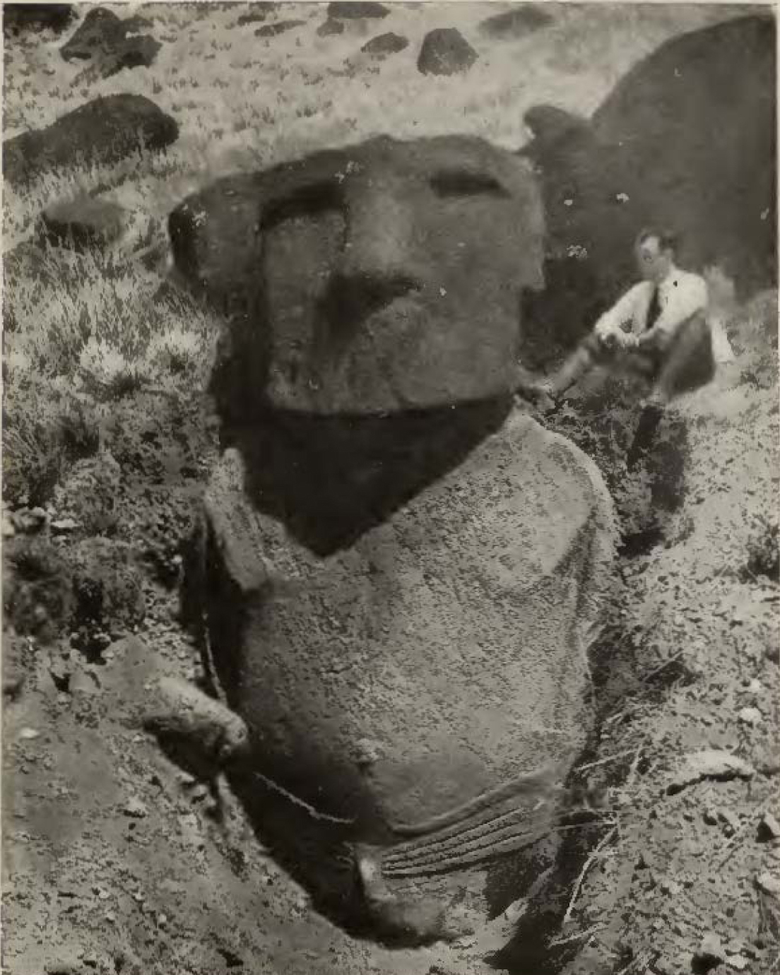 man sitting next to large stone statue in the ground