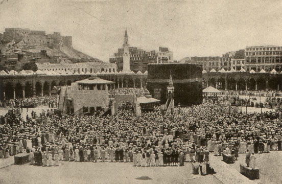 crowd of people facing a large black cube-shaped shrine
