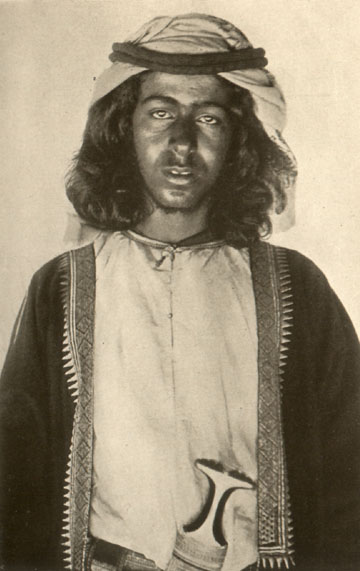 man with long hair in traditional Oman outfit and headdress
