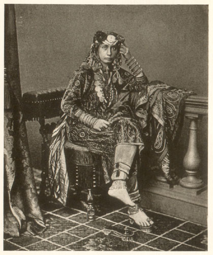 seated barefoot woman in ornate gown with headdress