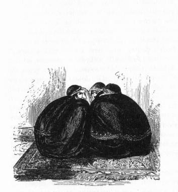 Women sitting on a carpet huddled in a circle.