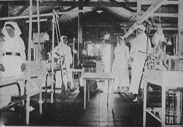 nurses standing in room filled with hospital beds