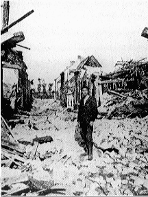 man standing atop the rubble of a bombed-out street