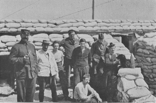 eight people and a dog in front of a trench made out of sandbags